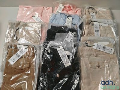 plusieurs paires de pantalons pour homme dans des sacs en plastique, posées sur une table
