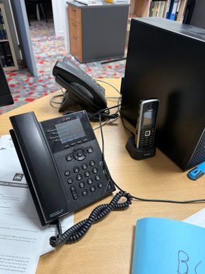 un bureau sur lequel se trouvent un téléphone, un ordinateur portable et un autre téléphone