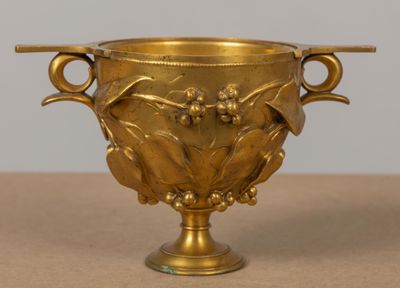 un vase en or à deux anses posé sur une table