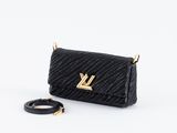 un sac Louis Vu noir avec des finitions dorées et une bandoulière en chaîne