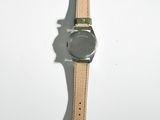 the watch is sitting on a white surface with a green strap