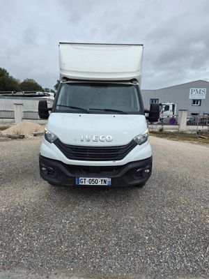 La camionnette blanche est garée sur le parking près d'un immeuble.