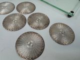 six silver coasters sitting on top of a table next to a glass shelf