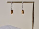 earrings on a gold stand with a marble bench in the background