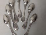 six silver spoons are arranged in a circle on a white surface
