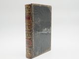 an old book sitting on top of a white table next to a white wall