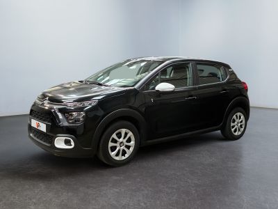 La voiture noire est garée dans une grande pièce au sol noir.