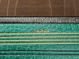 two pieces of green and black leather with a gold zipper