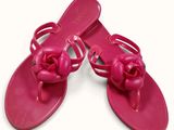 pair of pink sandals with bows on them on a white surface