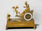 une horloge en or ornée d'anges et représentant un homme dans une calèche