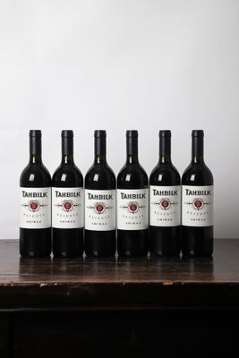 six bouteilles de vin sont alignées sur une table en bois