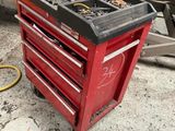 une boîte à outils rouge posée par terre à côté d'un camion