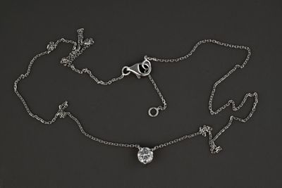 a silver necklace with a heart and a pair of scissors