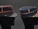 pair of hats on mannequin heads on display against a black background