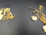 Deux bijoux en or sont posés sur une surface noire