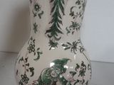 a white vase with green and white designs on it