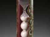 an hourglass with three white balls inside of it
