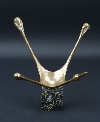 une sculpture représentant un oiseau, de couleur or et noir, posée sur un socle en marbre