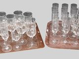 une paire de verres à vin transparents posés sur un socle en bois, sur fond gris