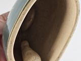 a hand holding a cup with a rock inside of it