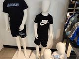 three mannequins in a clothing store display with shirts and shorts