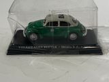 a small green car in a glass case on a white surface