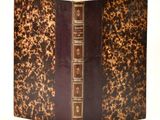 un vieux livre à la couverture marron posé sur une table blanche