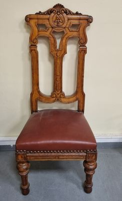 une vieille chaise en bois avec une assise en cuir marron, dans une pièce