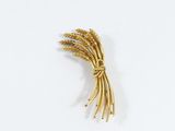 a gold brooch of wheat on a white surface