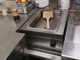stainless steel counter top in a commercial kitchen with a fryer and sink
