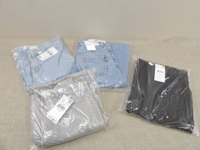 quatre paires de jeans sont emballées dans des sacs en plastique sur un canapé