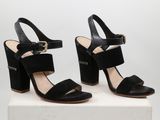 une paire de sandales noires à talons hauts posée sur un socle blanc