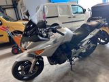 une moto argentée garée dans un garage à côté d'une camionnette