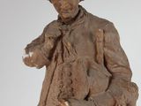 statue of a man with a hat and a coat holding a teddy bear