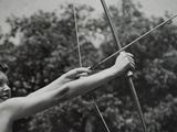 an old black and white photo of a woman holding a bow