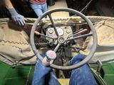 a man that is sitting in the driver ' s seat of a green car