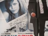 affiche représentant un homme en costume-cravate marchant devant une affiche représentant une femme