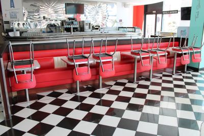 sol à carreaux noirs et blancs dans un snack-bar avec des banquettes rouges