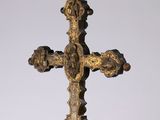une croix en or posée sur un socle, sur fond blanc