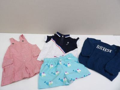 Trois paires de vêtements pour bébé sont posées sur une table blanche.