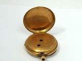 a gold pocket watch sitting on a white surface