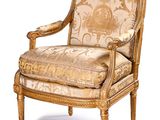 an upholstered chair with a gold and white patterned upholstered back