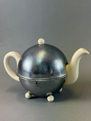 a silver teapot with a silver lid on a table