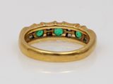 a close up of a gold ring with green stones