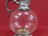 un vase en verre avec une anse en argent sur fond rouge