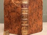 an old book sitting on top of a table next to a metal book holder