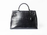 a black crocodile skin handbag on a white background