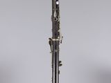 a black and gold clarinet on a clear pedestal with a gray background