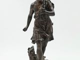 une statue en bronze représentant une femme tenant un chien, posée sur un socle en bois