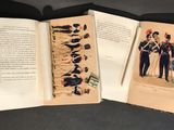 two open books with pictures of military uniforms on them on a table
